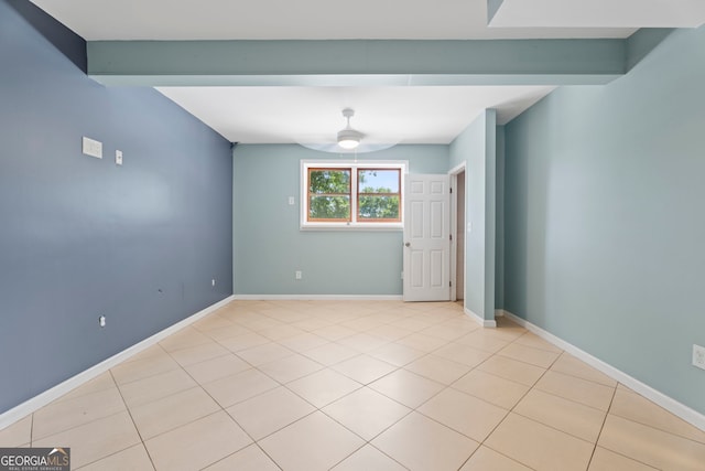 empty room featuring ceiling fan, light tile patterned flooring, and baseboards