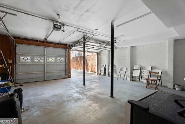 garage featuring a garage door opener and concrete block wall