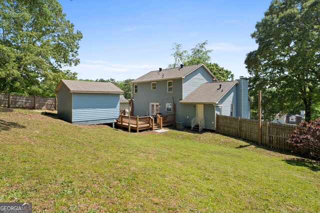 back of property featuring a deck, a storage shed, and an outbuilding