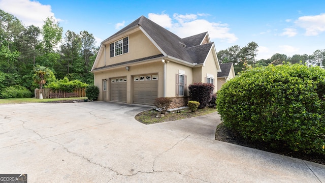 11440 Azalea Trl, Hampton, GA 30228 - view of side of property with fence, an attached garage, stucco siding, a shingled roof, and concrete driveway
