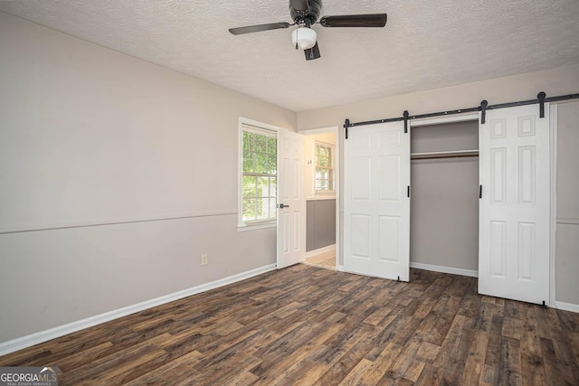 599 Honey Creek Rd, Conyers, GA 30094 - unfurnished bedroom with a barn door, dark wood-style floors, baseboards, a textured ceiling, and a closet