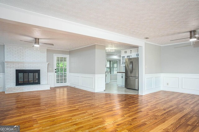 599 Honey Creek Rd, Conyers, GA 30094 - unfurnished living room featuring a ceiling fan, wood finished floors, a textured ceiling, a decorative wall, and wainscoting