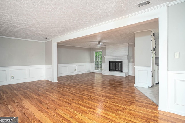 599 Honey Creek Rd, Conyers, GA 30094 - unfurnished living room featuring a ceiling fan, light wood-type flooring, a brick fireplace, wainscoting, and ornamental molding