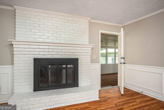 599 Honey Creek Rd, Conyers, GA 30094 - detailed view of a brick fireplace, wood finished floors, wainscoting, a textured ceiling, and ornamental molding
