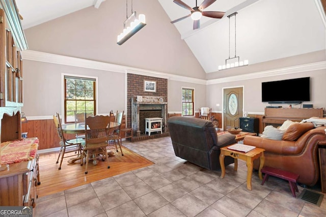 living room featuring high vaulted ceiling, a ceiling fan, wainscoting, and light tile patterned flooring