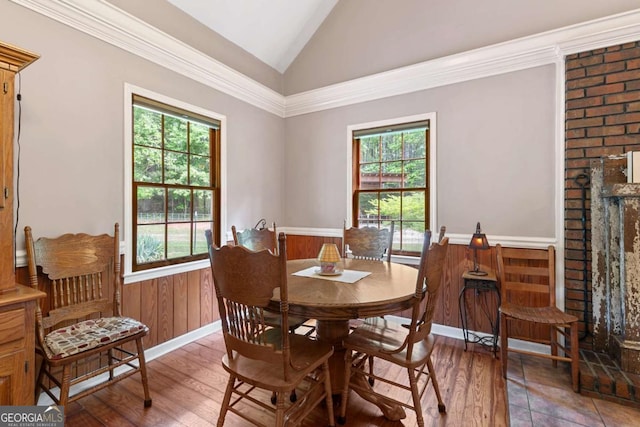 dining room with vaulted ceiling, a wainscoted wall, and light wood-style flooring