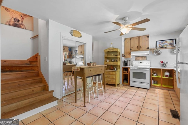 kitchen featuring white electric range, ceiling fan, under cabinet range hood, light tile patterned floors, and light countertops