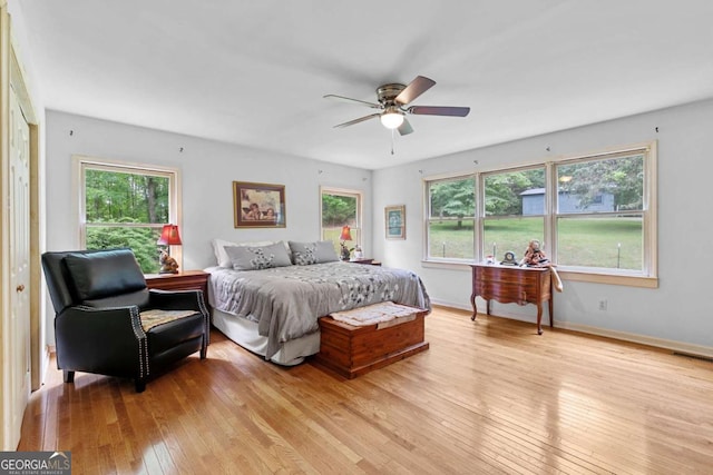 bedroom with light wood-style floors, multiple windows, baseboards, and a ceiling fan