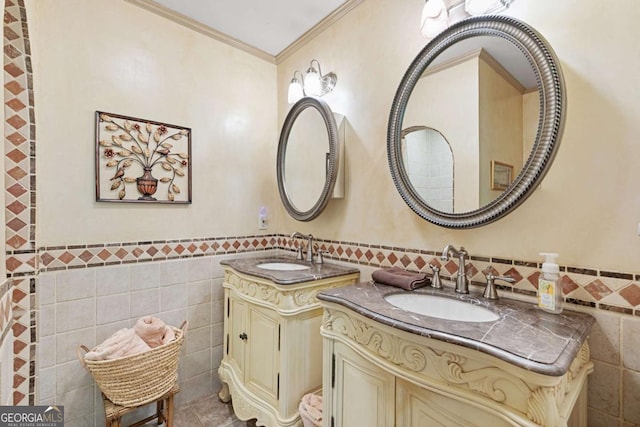 bathroom featuring tile walls, two vanities, a wainscoted wall, and crown molding