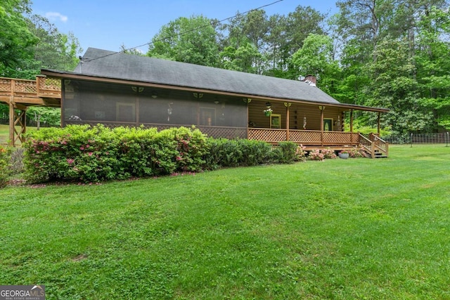 back of property with a sunroom, a chimney, and a wooden deck