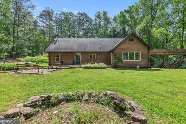 back of property featuring log siding, a yard, and a patio area
