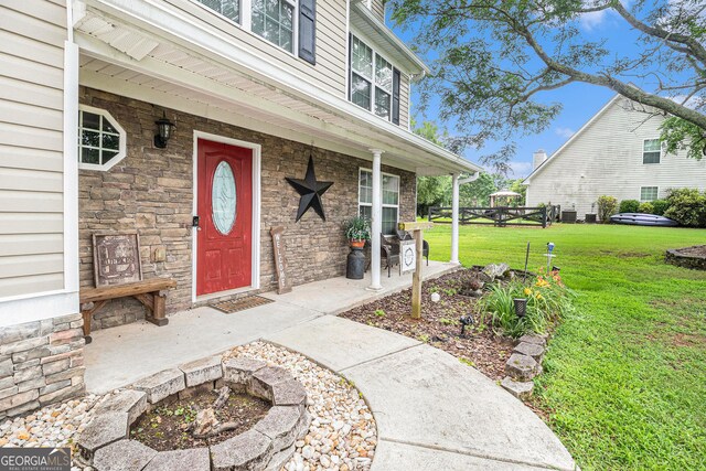 1071 Wildflower Way, Madison, GA 30650 - entrance to property with a lawn, stone siding, a porch, and central AC