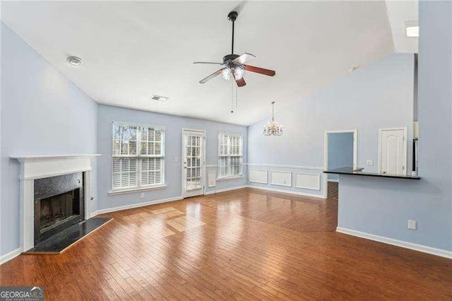 334 Hunterian Pl, Newnan, GA 30265 - unfurnished living room with visible vents, ceiling fan with notable chandelier, a high end fireplace, high vaulted ceiling, and wood finished floors