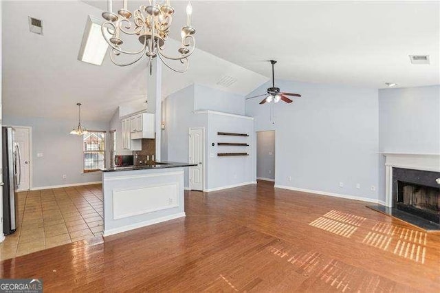 334 Hunterian Pl, Newnan, GA 30265 - unfurnished living room featuring ceiling fan with notable chandelier, high vaulted ceiling, a fireplace with raised hearth, and visible vents