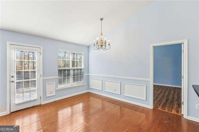 334 Hunterian Pl, Newnan, GA 30265 - unfurnished dining area with lofted ceiling, baseboards, an inviting chandelier, and wood finished floors