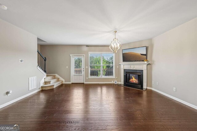 1257 Park Pass Way, Suwanee, GA 30024 - unfurnished living room with hardwood / wood-style floors, visible vents, an inviting chandelier, baseboards, and a glass covered fireplace