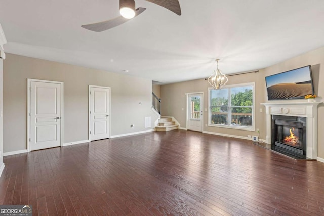 1257 Park Pass Way, Suwanee, GA 30024 - unfurnished living room featuring stairs, ceiling fan with notable chandelier, hardwood / wood-style floors, and a glass covered fireplace