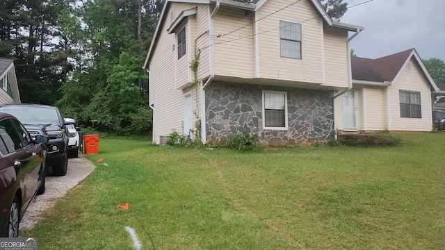 view of home's exterior with stone siding and a lawn