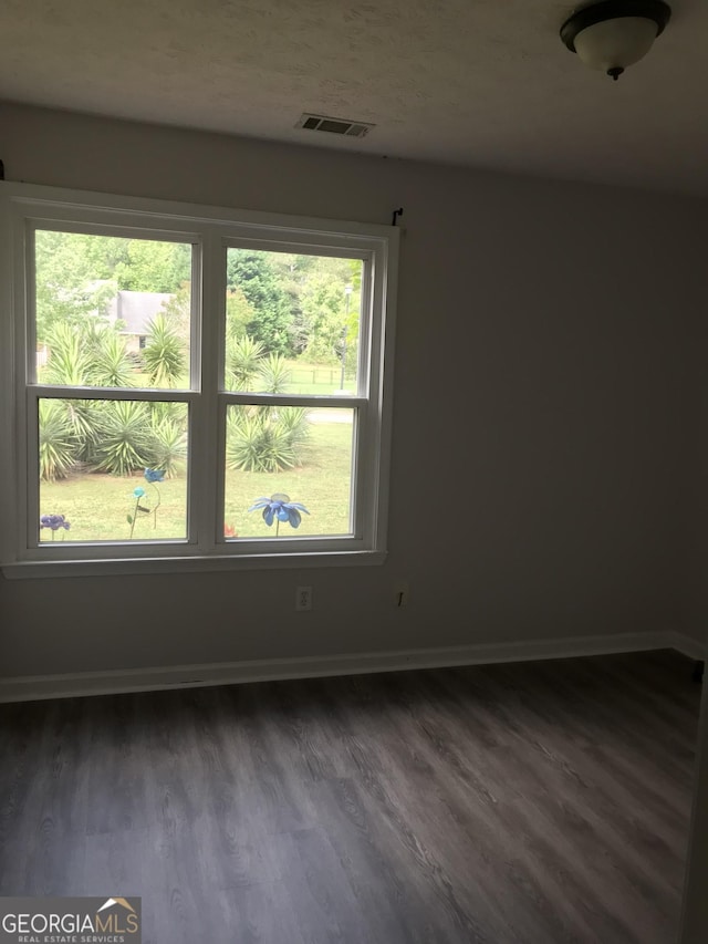 unfurnished room with dark wood finished floors, visible vents, and baseboards