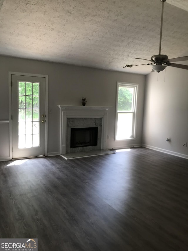 unfurnished living room with a textured ceiling, dark wood-style flooring, a ceiling fan, and a high end fireplace