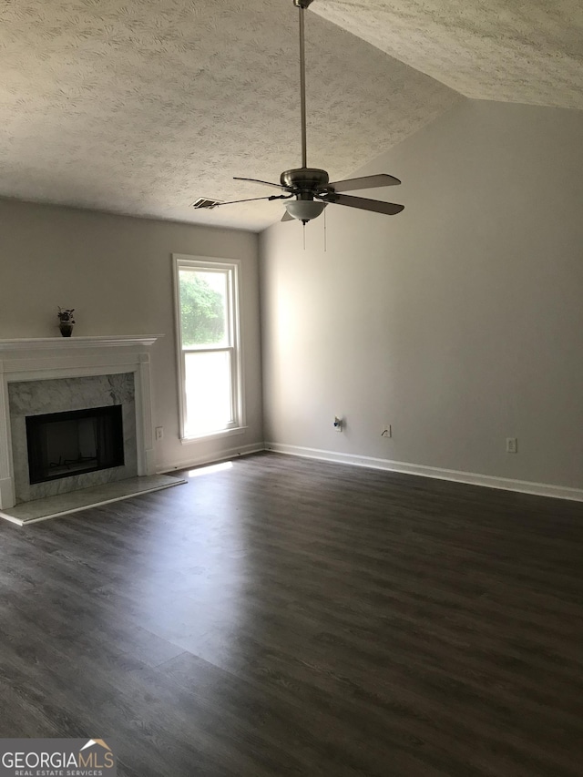 unfurnished living room featuring a ceiling fan, baseboards, dark wood finished floors, and a textured ceiling