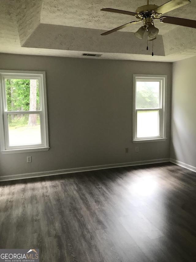 empty room with baseboards, a ceiling fan, and dark wood-type flooring
