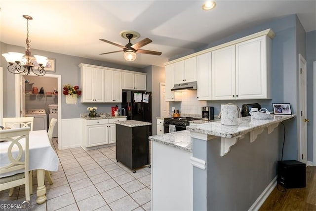 2759 Beddington Way, Suwanee, GA 30024 - kitchen featuring washing machine and clothes dryer, black appliances, a peninsula, under cabinet range hood, and a ceiling fan
