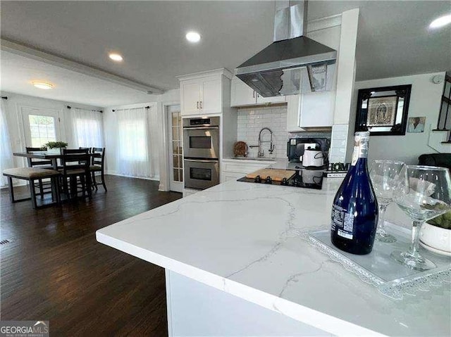 2638 Cleburne Pkwy, Powder Springs, GA 30127 - kitchen featuring recessed lighting, stainless steel double oven, light stone countertops, wall chimney range hood, and dark wood-style floors