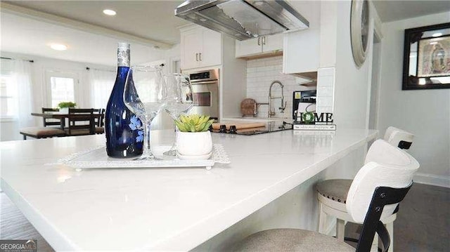 2638 Cleburne Pkwy, Powder Springs, GA 30127 - kitchen with a sink, black electric cooktop, a kitchen breakfast bar, under cabinet range hood, and stainless steel oven