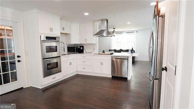 2638 Cleburne Pkwy, Powder Springs, GA 30127 - kitchen with tasteful backsplash, dark wood-style flooring, wall chimney range hood, stainless steel appliances, and white cabinets