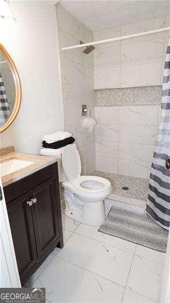 2638 Cleburne Pkwy, Powder Springs, GA 30127 - full bathroom with vanity, toilet, tiled shower, and tile patterned flooring