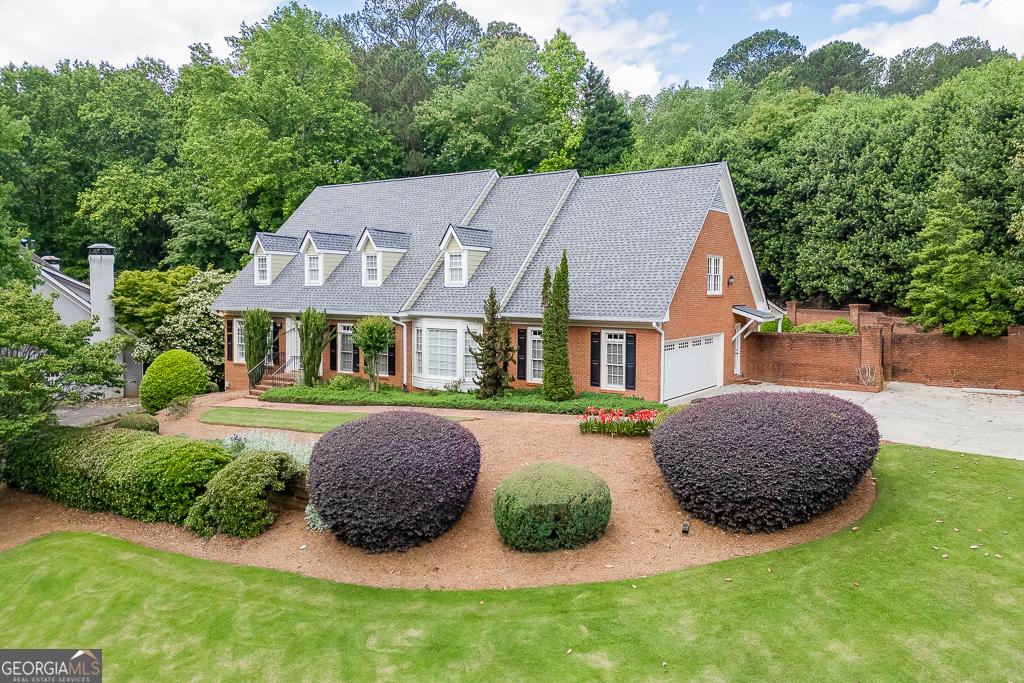 7660 Dunvegan Close, Sandy Springs, GA 30350 - new england style home with covered porch, fence, brick siding, driveway, and a front lawn