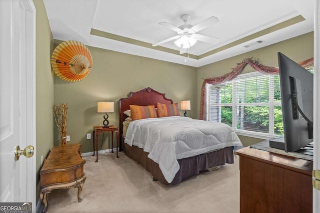 bedroom with light colored carpet, a raised ceiling, a ceiling fan, and baseboards