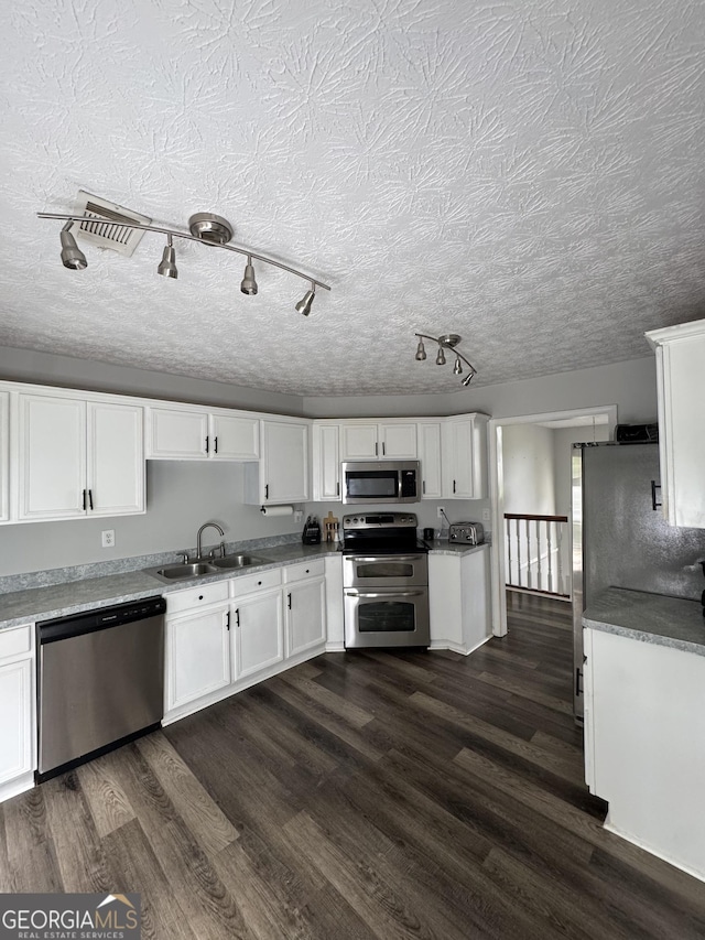 85 Creekside Trl, Covington, GA 30016 - kitchen featuring appliances with stainless steel finishes, white cabinetry, dark wood-style floors, and a textured ceiling