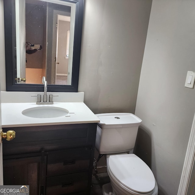 half bath featuring vanity and toilet