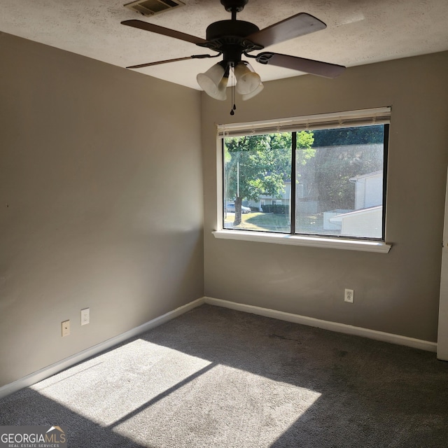 carpeted spare room with a textured ceiling, visible vents, baseboards, and ceiling fan