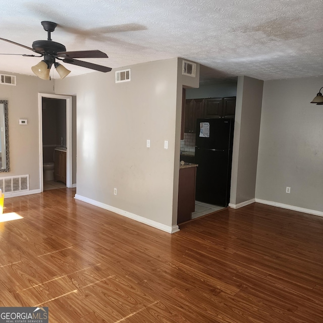 unfurnished living room featuring visible vents, baseboards, and a ceiling fan