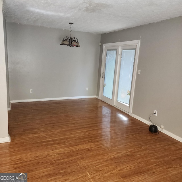 interior space featuring baseboards, a chandelier, a textured ceiling, and wood finished floors