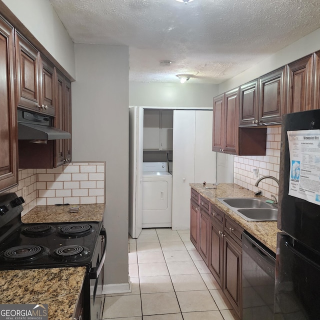 kitchen featuring a sink, washer / dryer, black appliances, under cabinet range hood, and backsplash