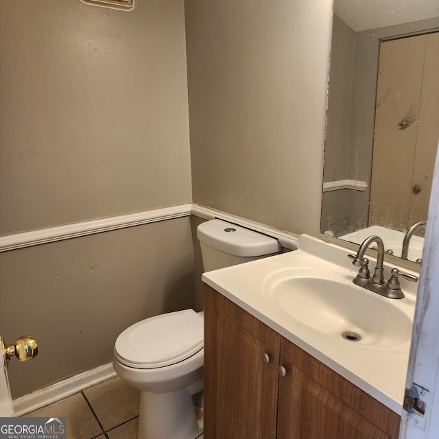half bath featuring toilet, tile patterned flooring, and vanity