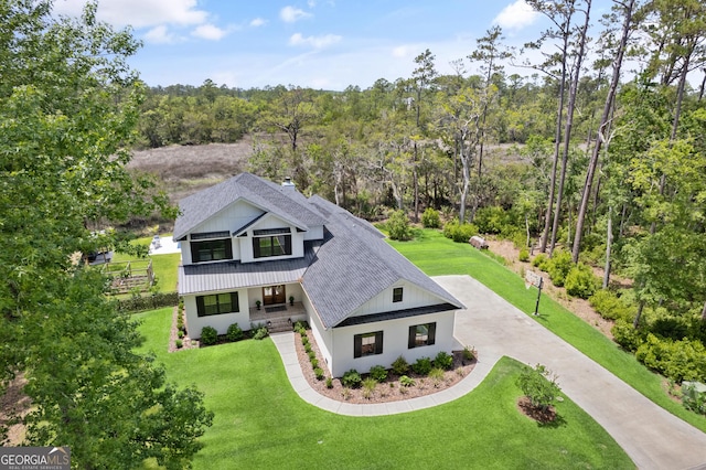 exterior space with concrete driveway, a front yard, a porch, and roof with shingles
