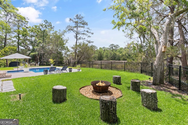 view of yard with an outdoor fire pit, fence, a fenced in pool, and a patio area