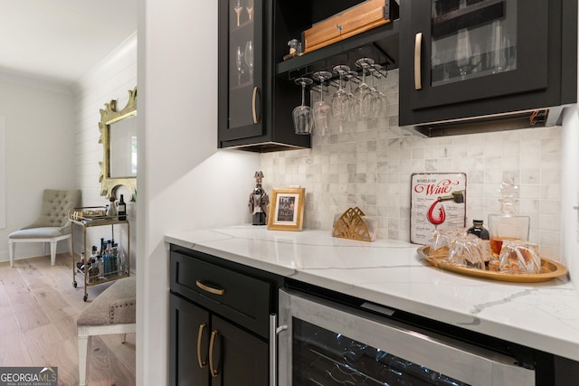 bar with a bar, tasteful backsplash, light wood-type flooring, and beverage cooler
