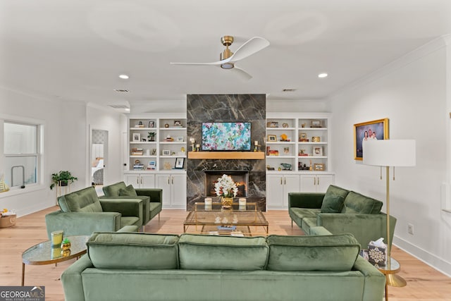living area featuring crown molding, ceiling fan, a high end fireplace, light wood-style floors, and recessed lighting