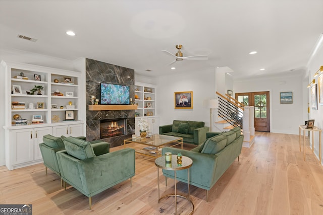 living area featuring light wood-style floors, visible vents, and ornamental molding