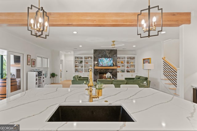 kitchen featuring a high end fireplace, light stone counters, open floor plan, and a sink