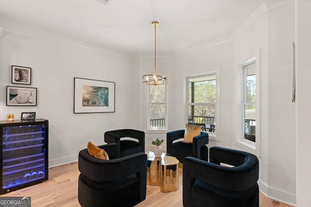 sitting room with wine cooler, ornamental molding, and light wood-style floors