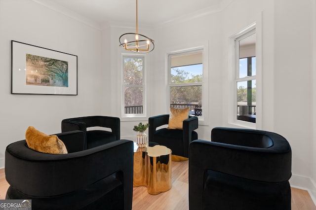 living area with wood finished floors, ornamental molding, and a notable chandelier