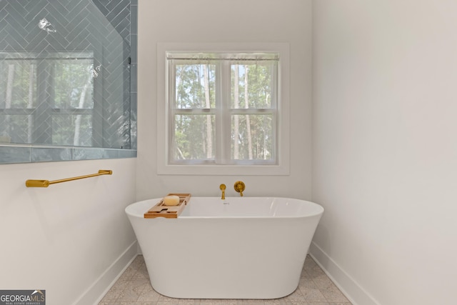 bathroom with baseboards, tiled shower, and a freestanding tub