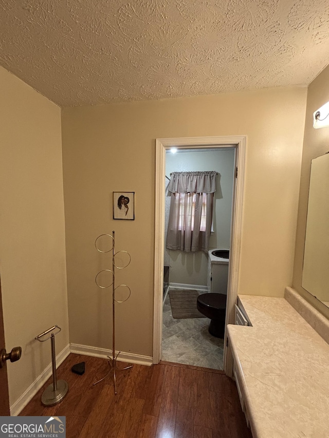 bathroom with hardwood / wood-style flooring, a textured ceiling, toilet, and baseboards